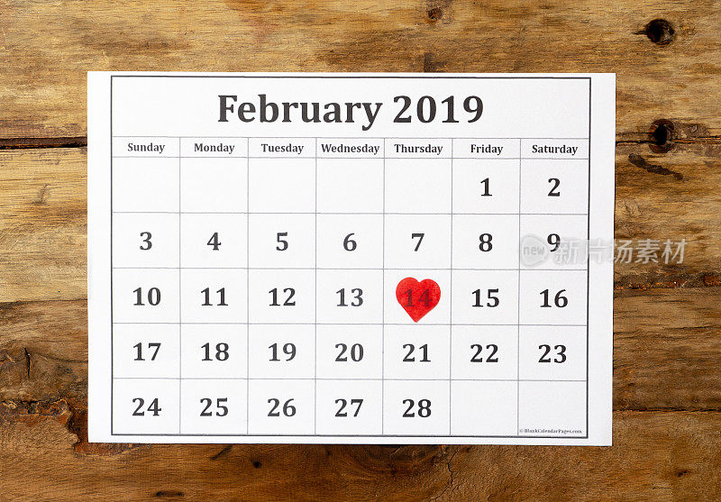 Calendar page with red heart on February 14 th of Saint Valentines day on vintage wooden rustic background in Romantic love Celebration and Valentine's Day greetings card design concept. Top view.